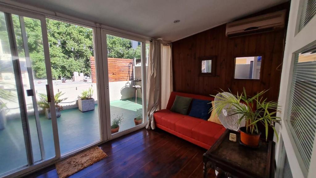 uma sala de estar com um sofá vermelho e uma grande janela em Terracita /mini casa centrica em Mendoza
