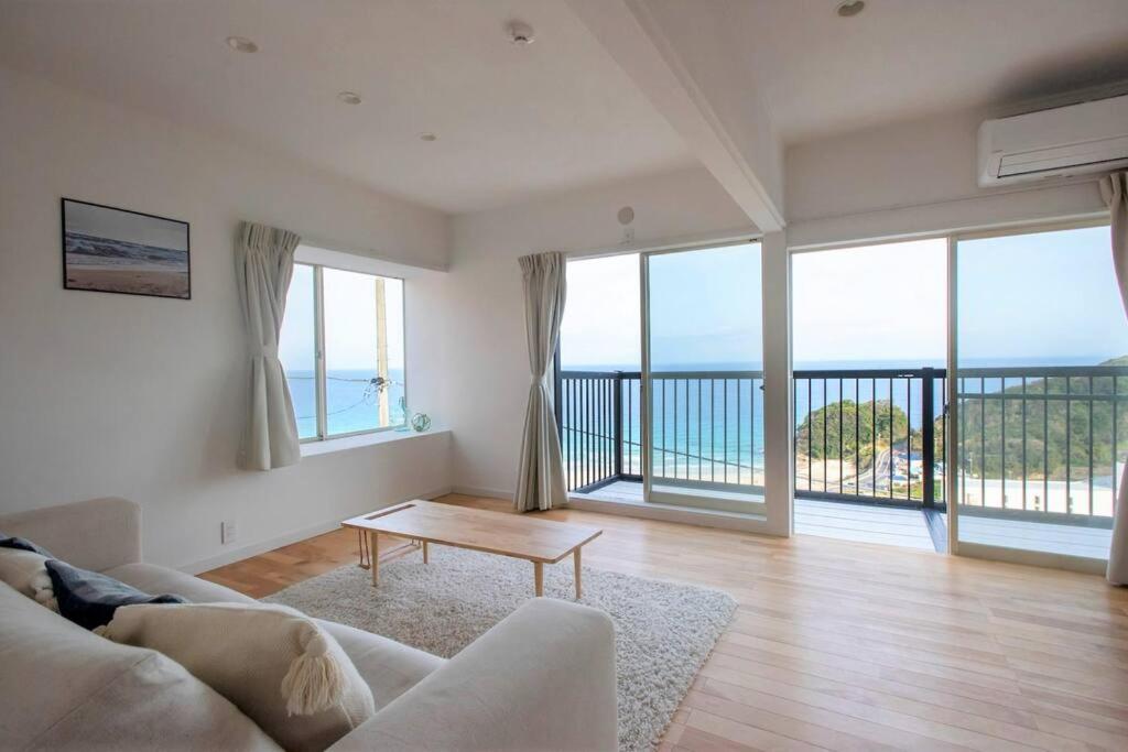 Sala de estar con sofá y vistas al océano en Sirahama Beach House en Shimoda