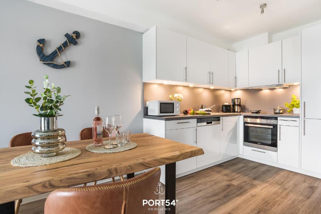 a kitchen with white cabinets and a wooden table at Meerzeit Damp in Damp