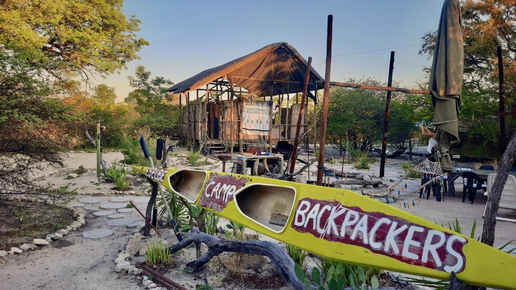 een gele surfplank voor een houten huis bij Eselbe Camp Backpackers in Nata