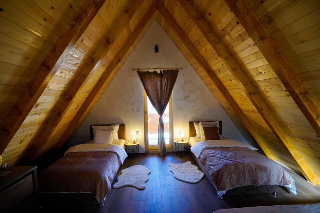 Cette chambre mansardée comprend 2 lits et une fenêtre. dans l'établissement Sunset Lux Cottage Ravna Planina Pale - Jahorina, à Pale