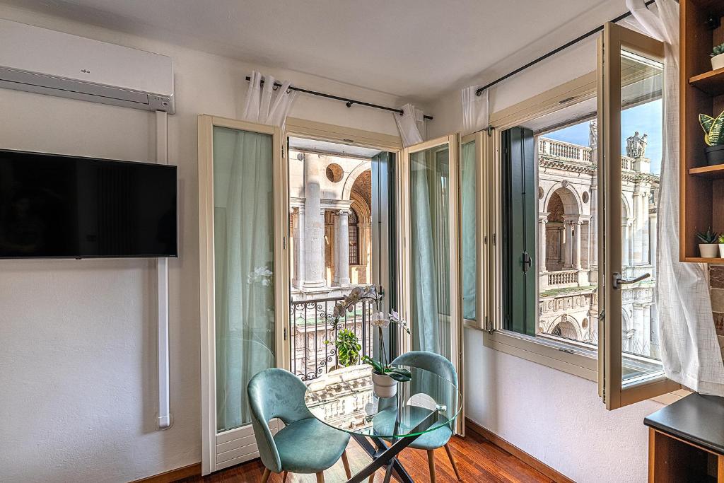 una camera con un tavolo in vetro, sedie e una finestra di Suite Palladiana, la migliore vista di Vicenza a Vicenza