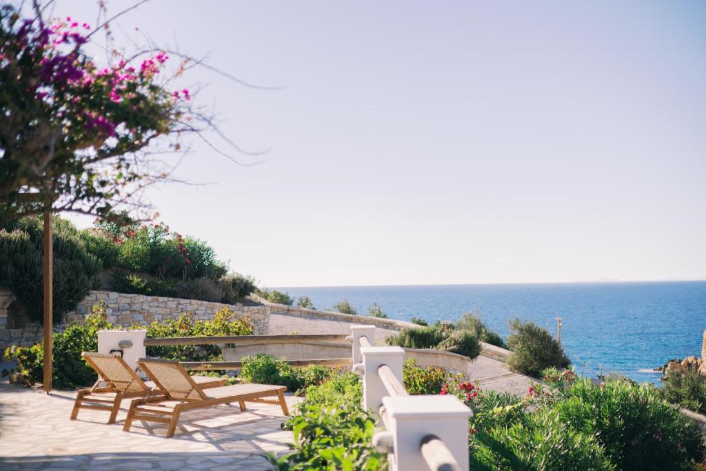 a patio with chairs and the ocean in the background at Mikra Bay Vineyard Guesthouses in Naxos Chora