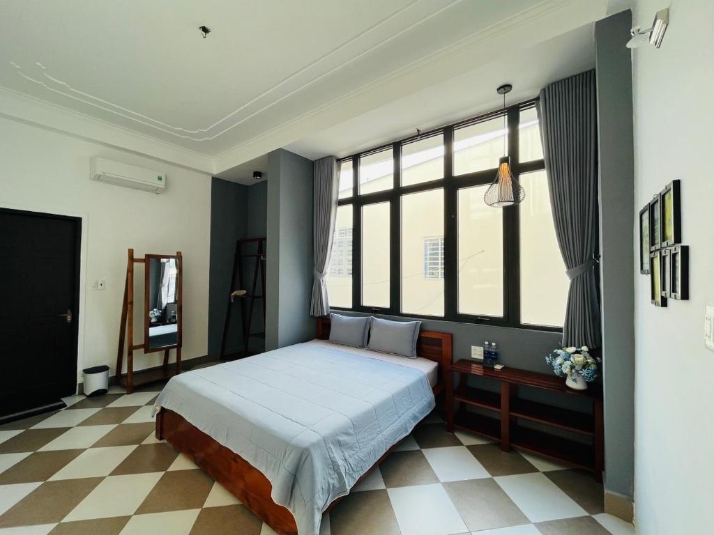 - une chambre avec un lit et une grande fenêtre dans l'établissement Queenie House, à Cần Thơ