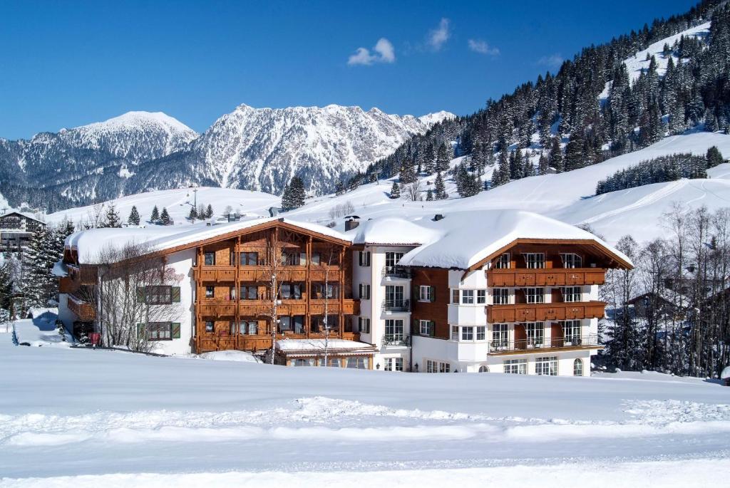 a hotel in the snow with snow covered mountains at Hotel Bogner Hof in Tannheim