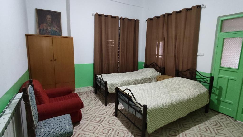 a room with two beds and a red chair at Issa's House in Beit Sahour