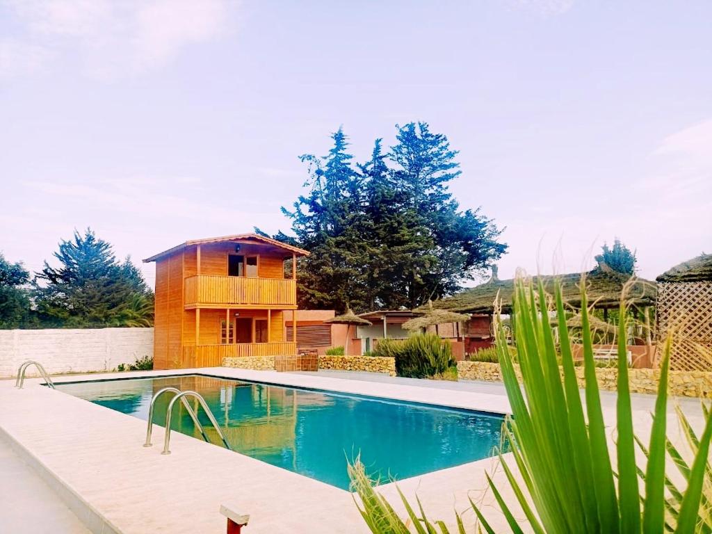 a swimming pool in front of a house at Ferme Sacrée Nature in Ben Slimane
