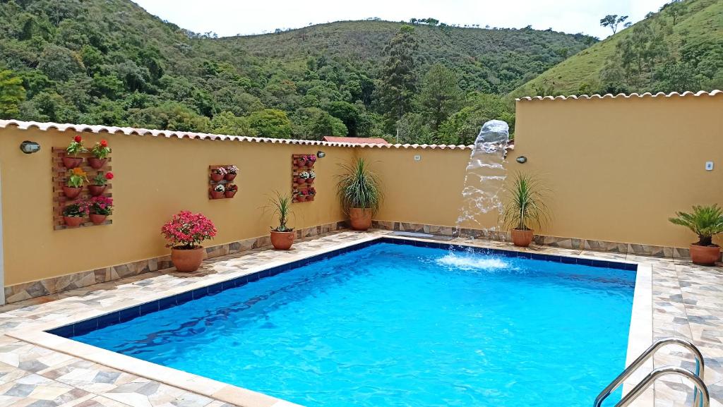 a swimming pool with a waterfall in front of a house at Pousada Alejandro in Cunha