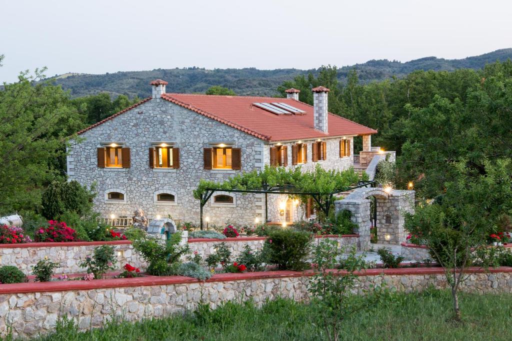 a stone house with a stone wall and flowers at Farma Sarli in Monódhrion