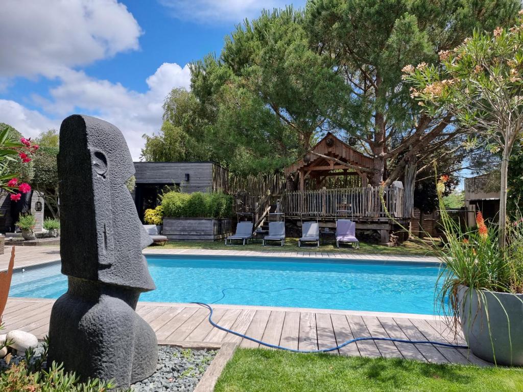 a statue sitting next to a swimming pool at Le Clos des Romarins in Saint-Palais-sur-Mer