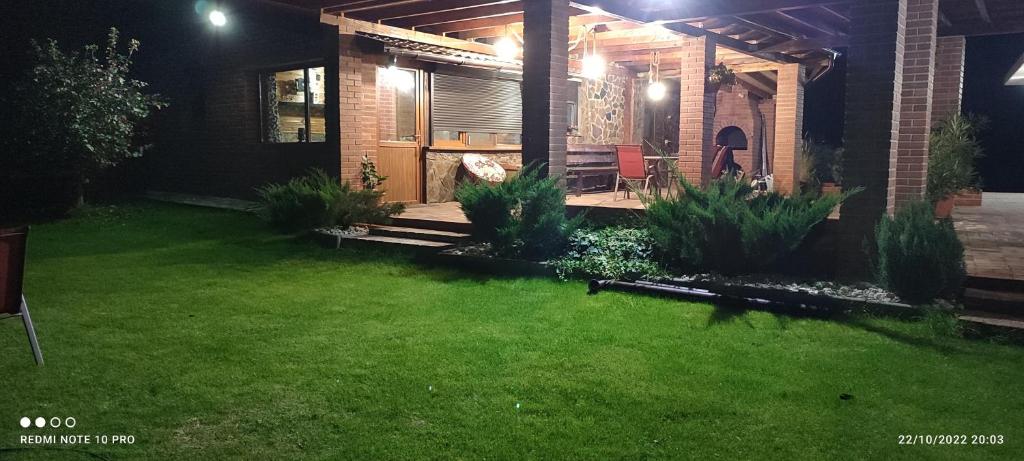 a backyard at night with green grass and a house at View Cozia in Călimăneşti