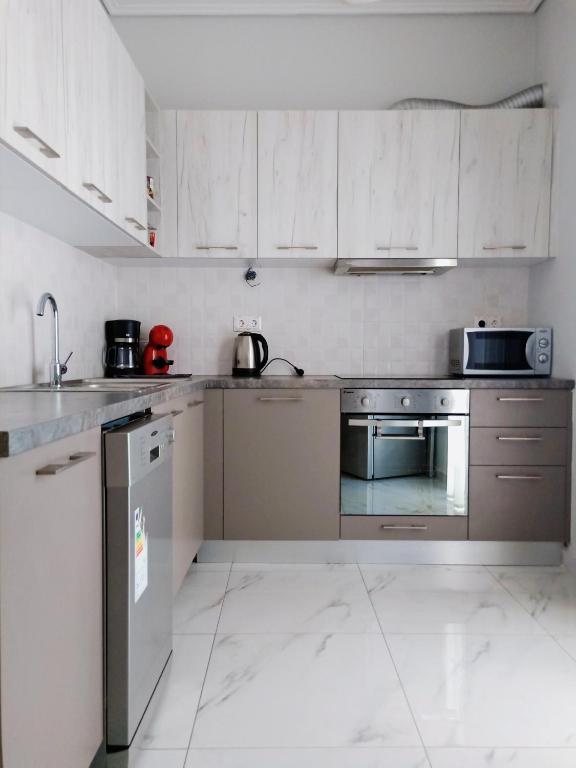 kuchnia z białymi szafkami i urządzeniami ze stali nierdzewnej w obiekcie Siggrou apartment w Atenach