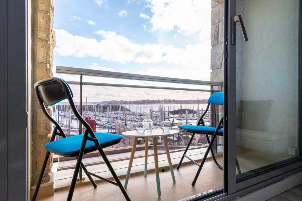 balcón con 2 sillas, mesa y ventana en Marée Tropicale - vue mer, en Saint-Cast-le-Guildo