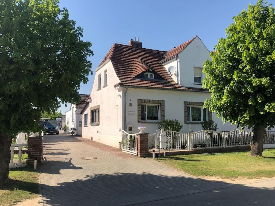 a white house with a fence on a street at Ferienwohnung in Golßen/Spreewald, Tropical Island in Golßen