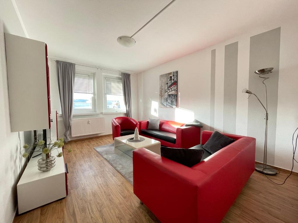 a living room with red chairs and a red couch at Ferienwohnung Heidebreite in Wernigerode