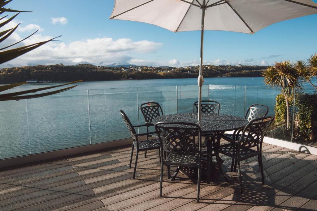 a table and chairs on a deck with a view of the water at The Ridge in Menai Bridge