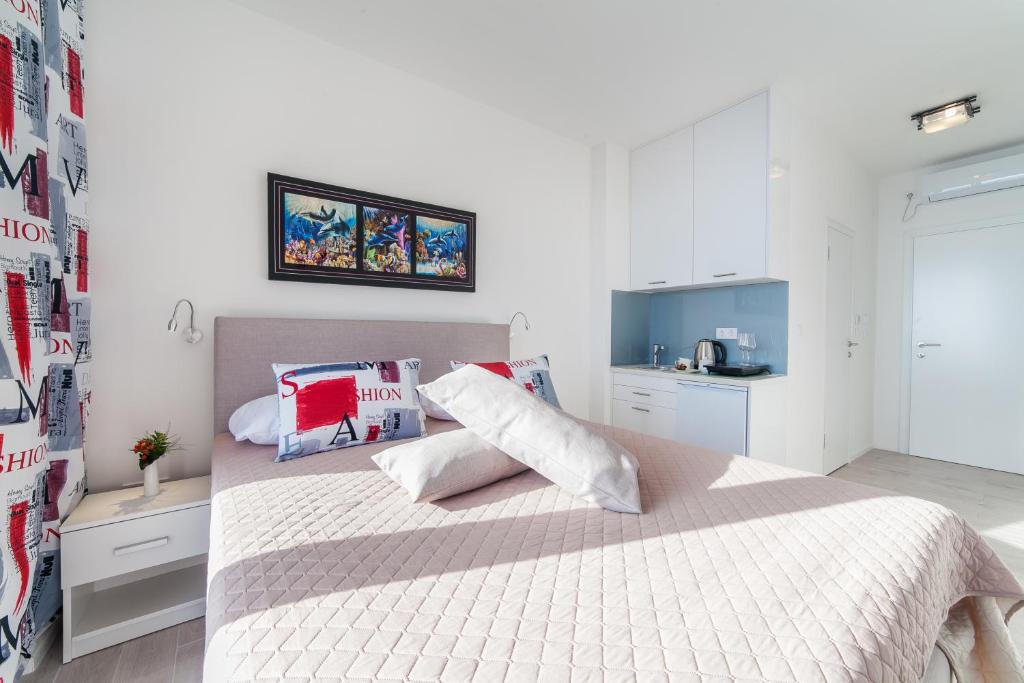 a white bedroom with a bed with white sheets and pillows at Villa Mona 2 in Budva