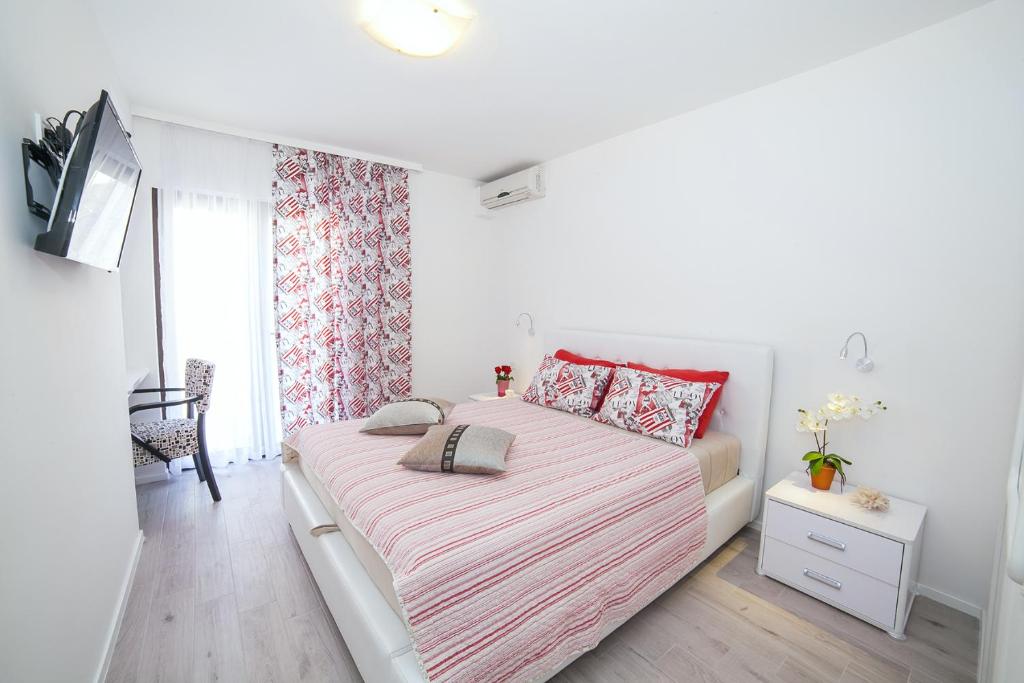 a white bedroom with a large bed with red pillows at Villa Mona 2 in Budva
