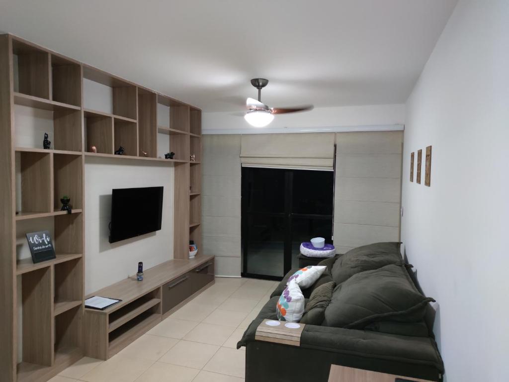 a living room with a couch and a television at Apartamento Rio das Ostras, Extensão do Bosque in Rio das Ostras