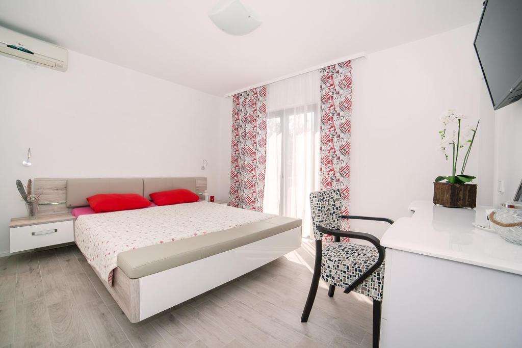a bedroom with a bed with red pillows and a window at Villa Mona 2 in Budva