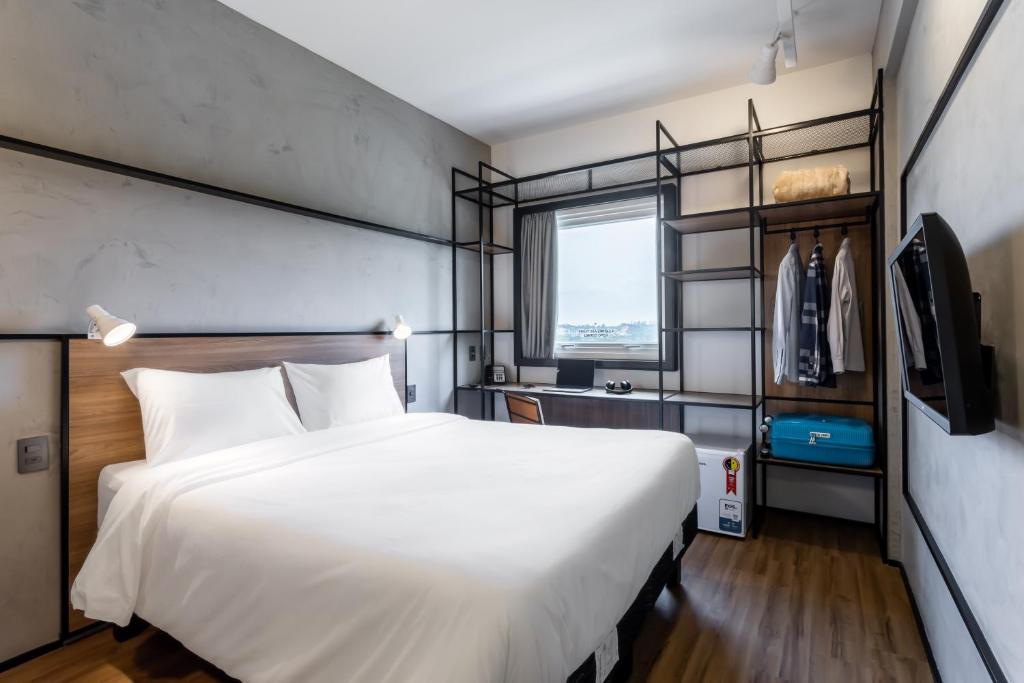 a bedroom with a large white bed and a window at Ibis Aruja in Arujá