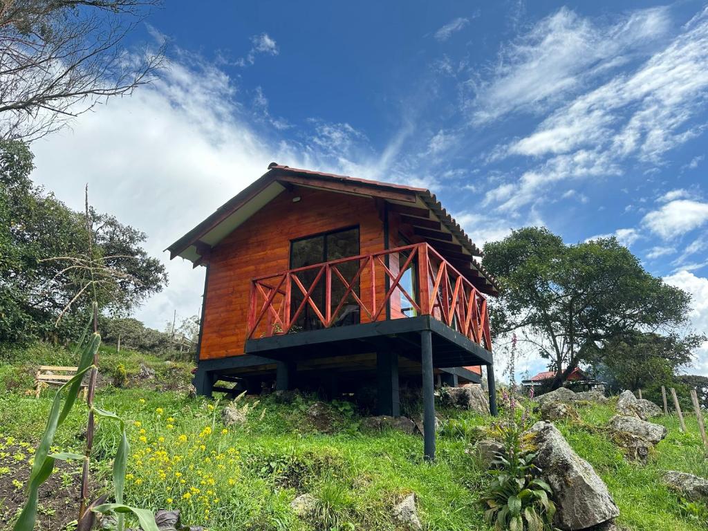 a small wooden house on a grassy hill at Rincón Entre Piedras-Cabaña Entre Montañas in Choachí