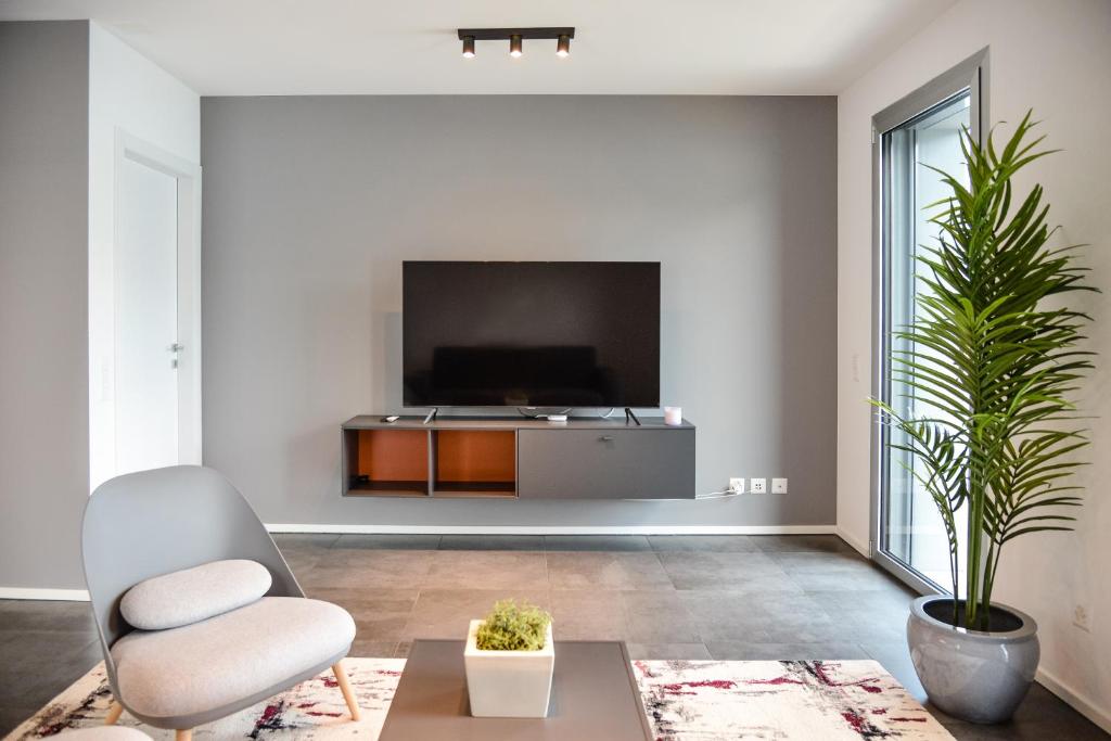 een woonkamer met een tv en een stoel bij Front Lake Apartment Meli With View Feel Ticino Feel Home in Melide