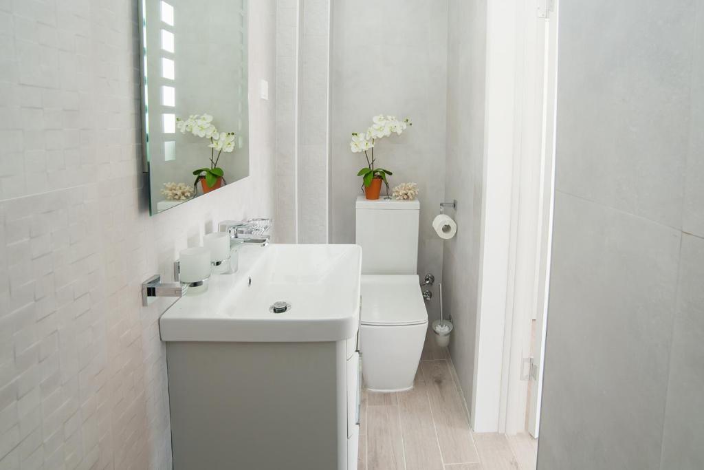 a white bathroom with a toilet and a sink at Villa Mona 2 in Budva