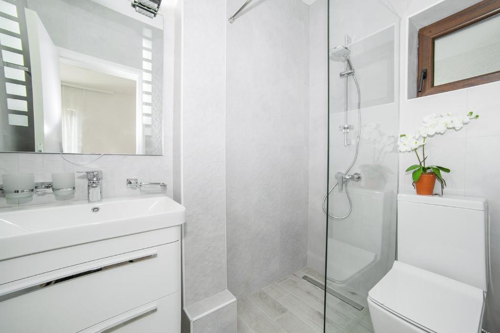 a white bathroom with a sink and a shower at Villa Mona 2 in Budva