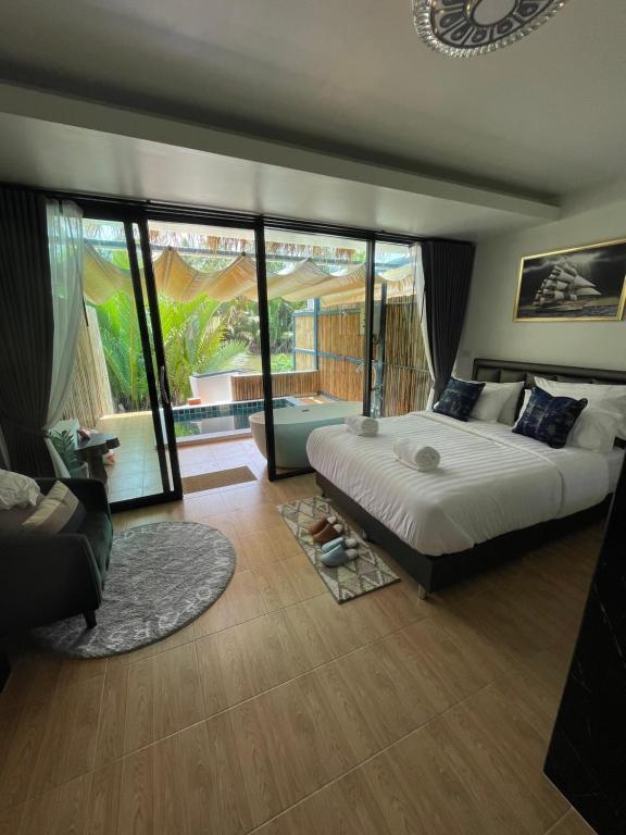 a bedroom with a large bed and a large window at Phetra pool villas in Surat Thani