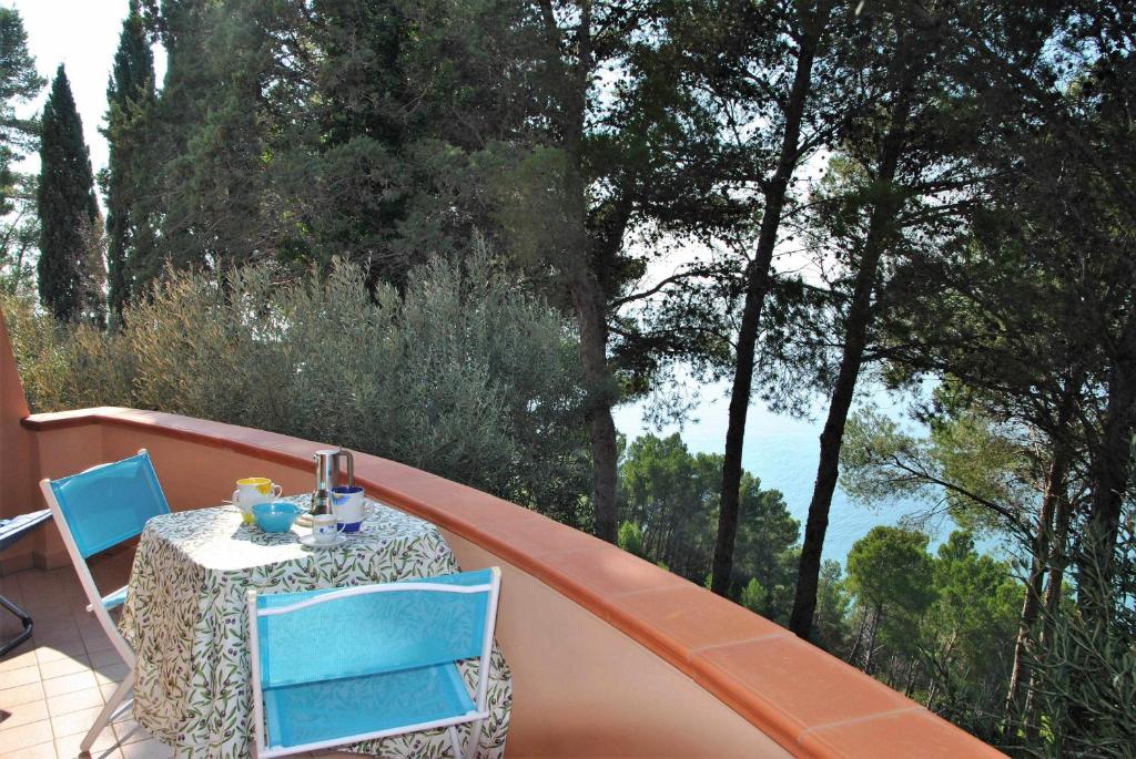 een tafel en stoelen op een balkon met bomen bij La Sirenetta tra mare e collina in Sperlonga