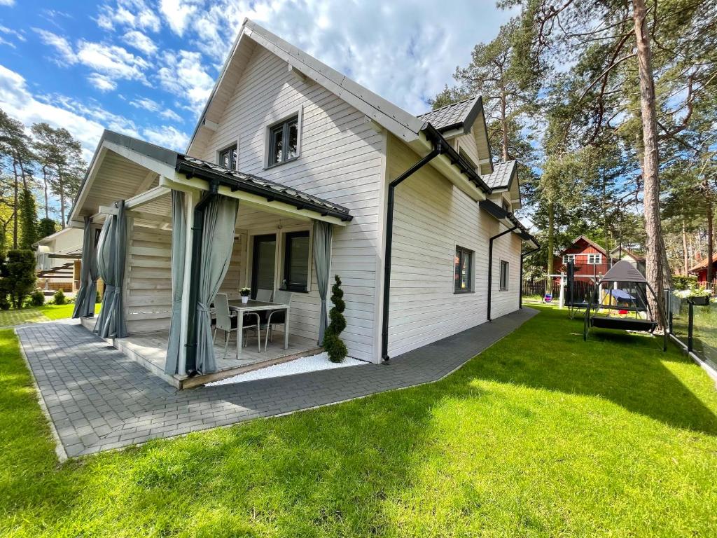 a white house with a patio on a lawn at AJ Apartments in Pobierowo