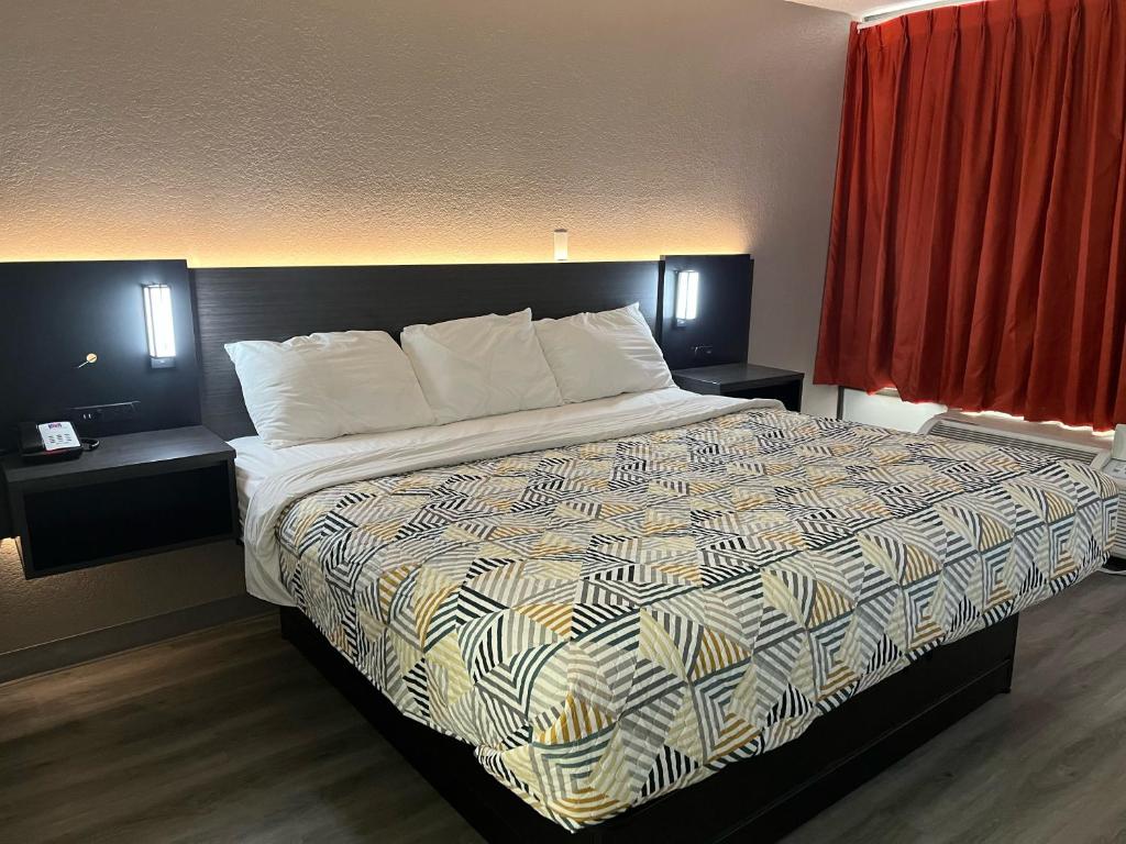 een groot bed in een hotelkamer met 2 nachtkastjes bij Motel 6 Baton Rouge Southeast in Baton Rouge
