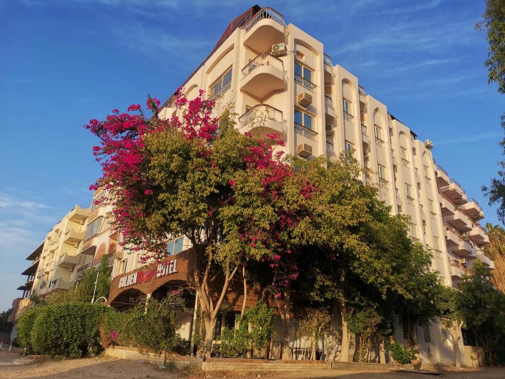 a large building with flowering trees in front of it at Golden Rose Hotel in Hurghada