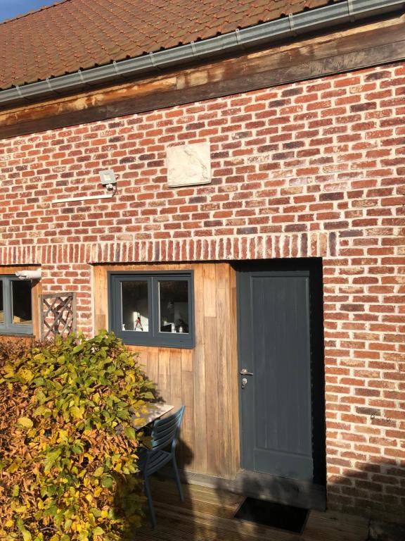 a brick building with a black door and a bench at Appartement lumineux et calme in Jodoigne