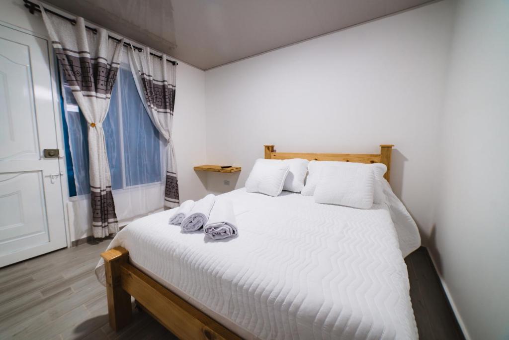 Un dormitorio con una cama blanca con toallas. en Hotel Alameda Plaza, en Cali