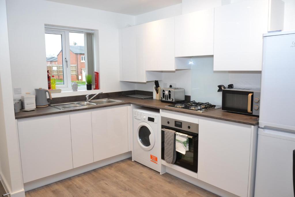 a kitchen with white cabinets and a washer and dryer at Erasmus House - 3 Bedrooms - City Centre, Netflix, WIFI, Free Private Parking in Derby