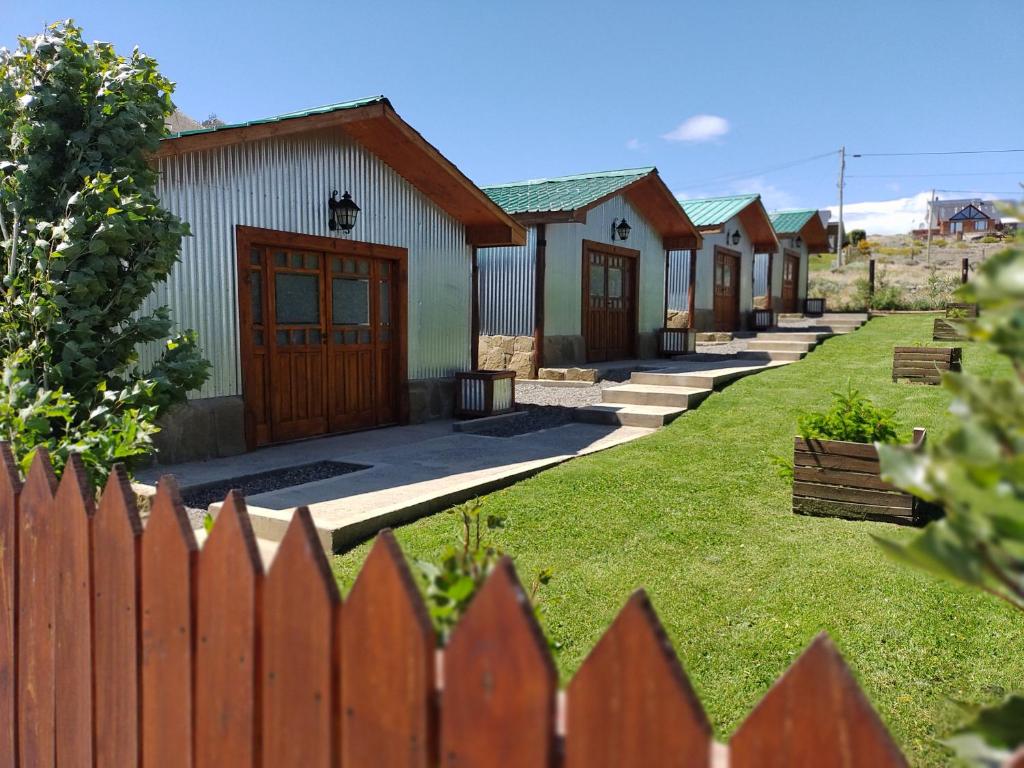 una fila de casas detrás de una valla de madera en Cabañas Ventalia en El Calafate