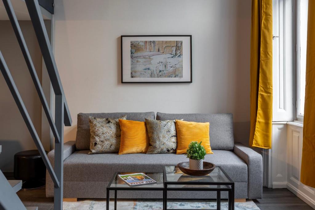 sala de estar con sofá gris y almohadas de color naranja en Global Living - Deluxe Rakoczi Residence By Bella, en Budapest