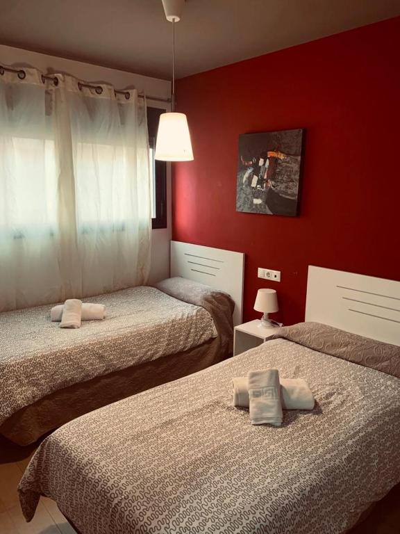 dwa łóżka w pokoju z czerwonymi ścianami w obiekcie Apartamentos 16:9 Suites Almería w mieście Almería