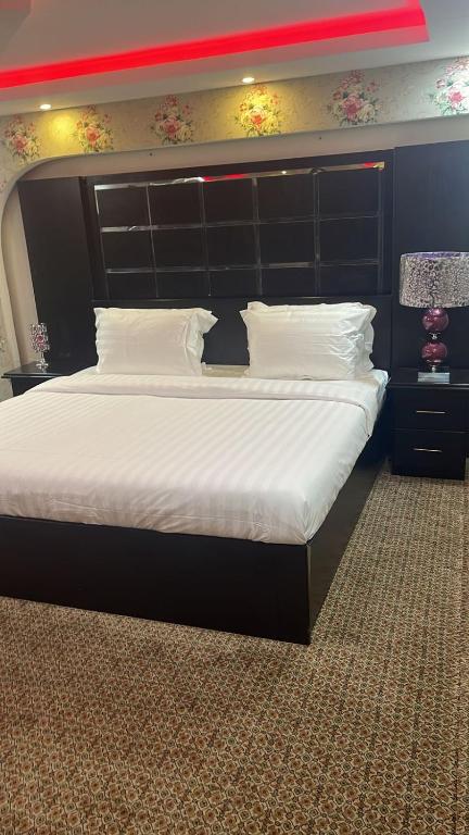 هوتيل حايل للشقق المفروشة يتوفر شهري سنوي في حائل: غرفة نوم مع سرير كبير مع اللوح الأمامي الأسود