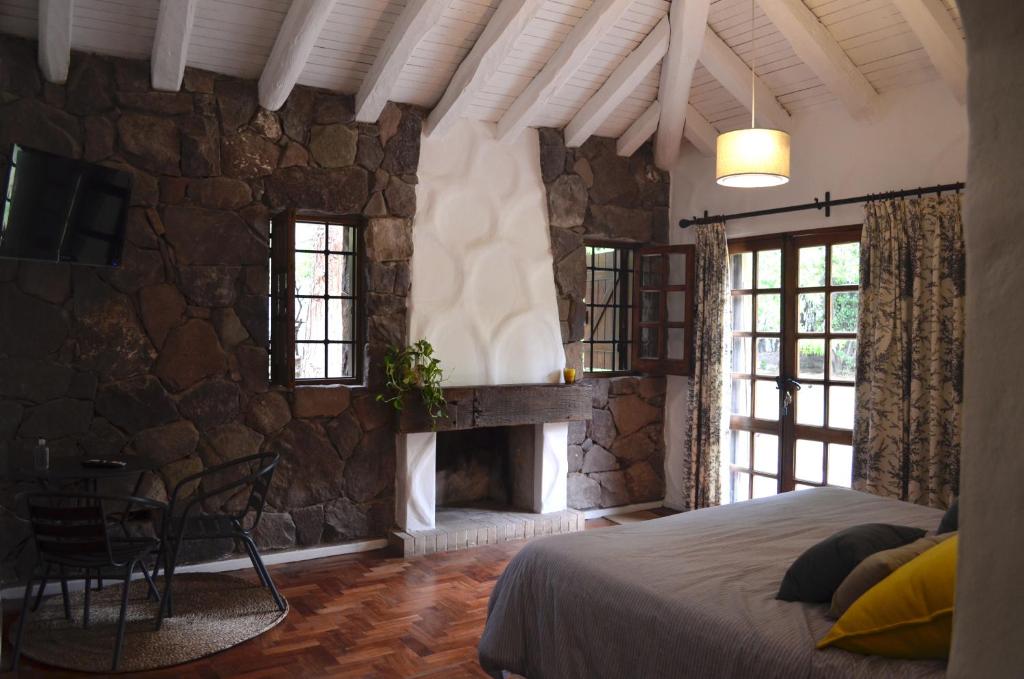 a bedroom with a stone wall with a bed and a fireplace at Alto Chacras Cottage in Chacras de Coria