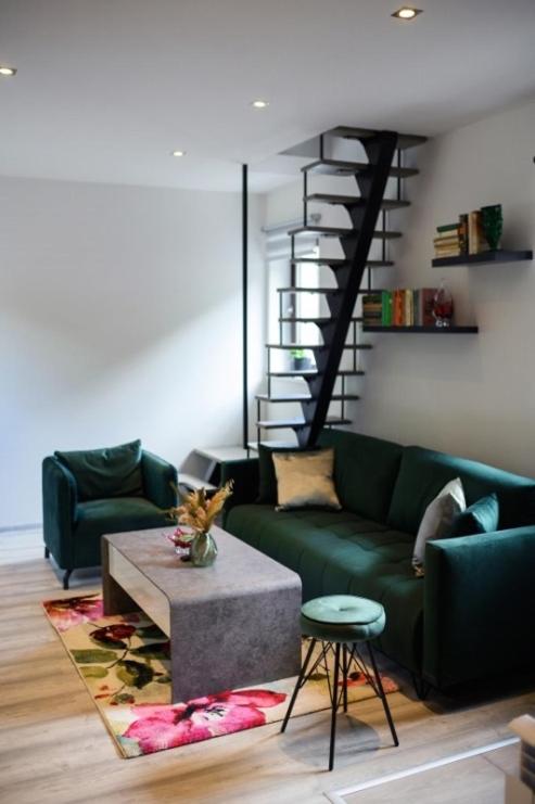 a living room with a green couch and a staircase at Apartman Kateřinky Liberec in Liberec