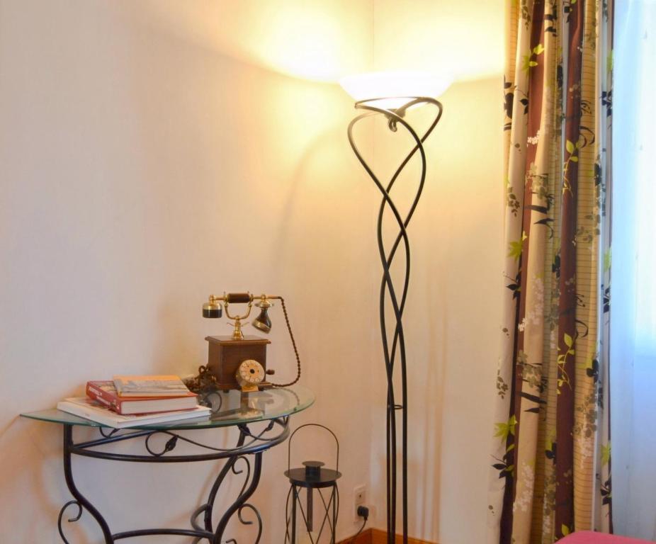 a floor lamp in a corner of a room with a table at Pavillon de 4 couchages, très calme, proche centre ville in Albi