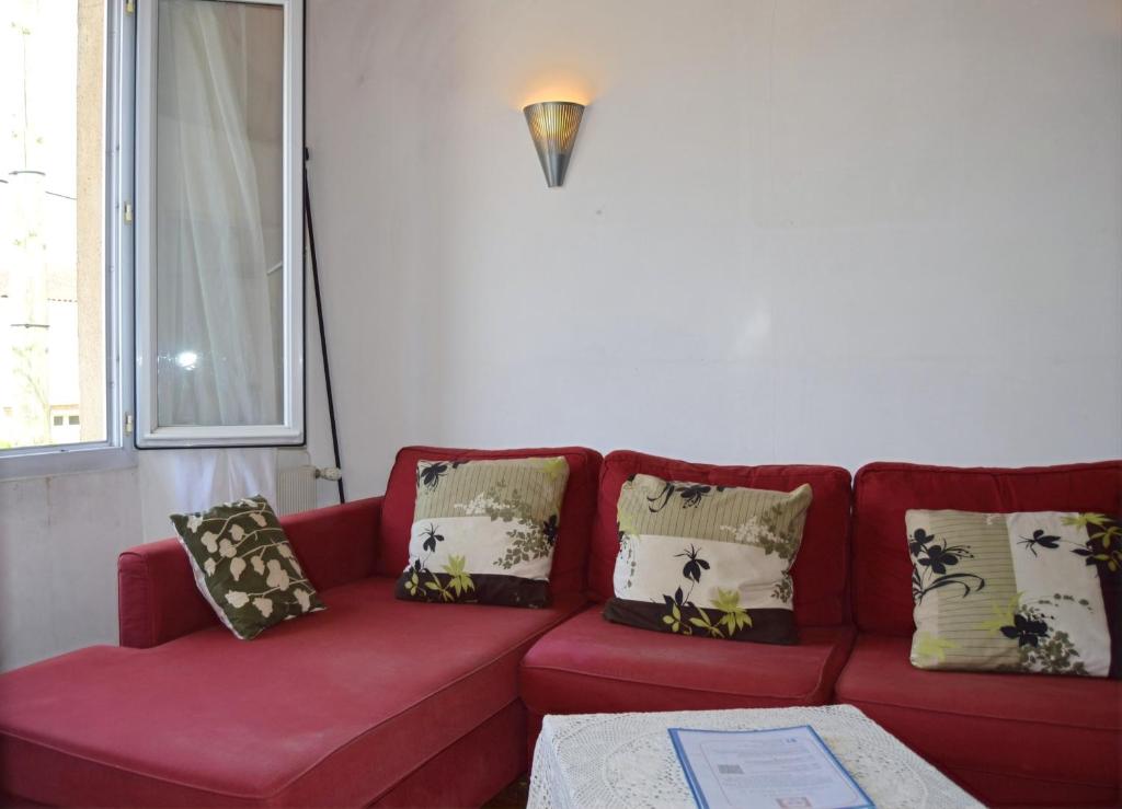 a red couch with pillows on it in a living room at Pavillon de 4 couchages, très calme, proche centre ville in Albi