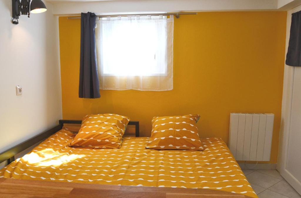 a bedroom with a bed with yellow walls and a window at Pavillon de 4 couchages, très calme, proche centre ville in Albi