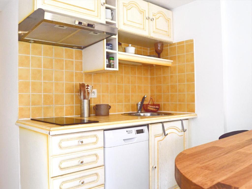 a kitchen with white cabinets and a sink and a table at Pavillon de 4 couchages, très calme, proche centre ville in Albi