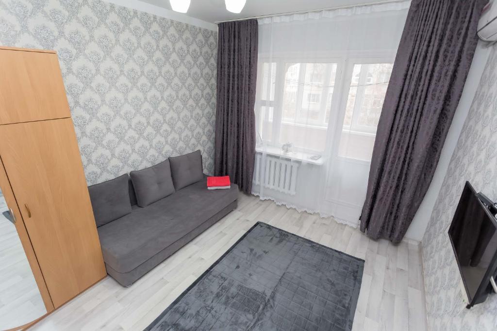 een woonkamer met een bank en een tv bij Апартаменты на Сатпаева in Alma-Ata