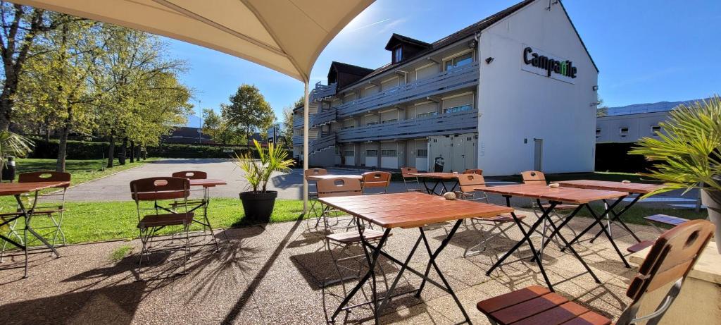 um grupo de mesas e cadeiras em frente a um edifício em Campanile Chambéry em Chambéry