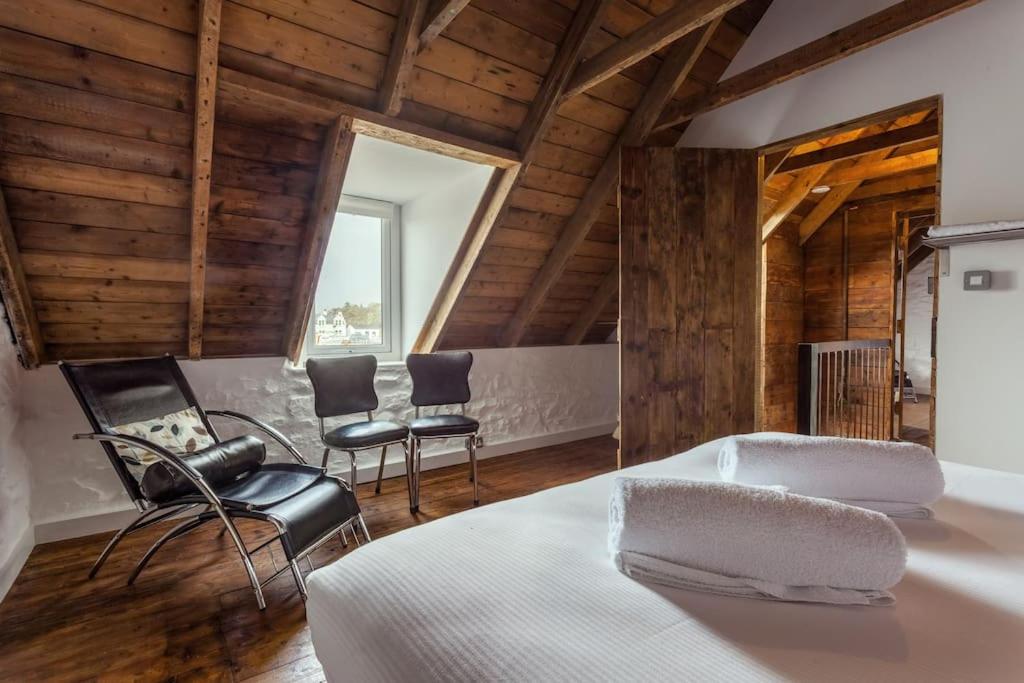 a bedroom with a bed and chairs in a room with wooden ceilings at Isle of Skye Cottage in Kyleakin